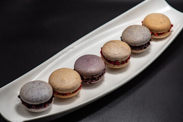 Set of delicious macaroons expensive candies on the black background