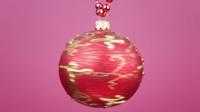 red christmas ball rotating close-up against pink background
