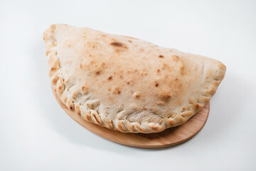 Italian pizza calzone on a wooden board. Italian pie in closed form of pizza made in the shape of a crescent. Italian fast food delivery.