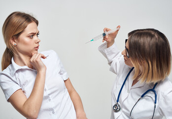 Female doctor shows the patient a syringe and a medical gown a stethoscope 