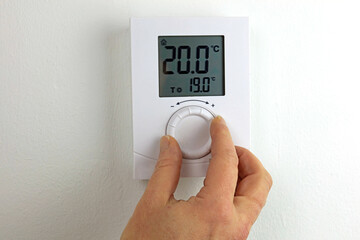hand with thermometer controlling a homes heating. - obrazy, fototapety, plakaty