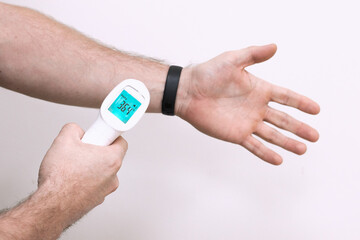 Man is measuring temperature himself using digital infrared thermometer at hand wrist