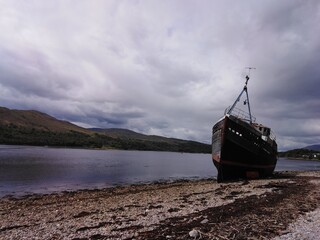 Old fishing boat by the sea with montains background