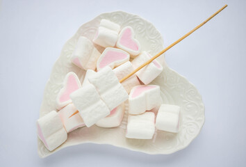 Heart-shaped marshmallow on a white plate on a white background. The concept of mother's Day, Valentine's Day