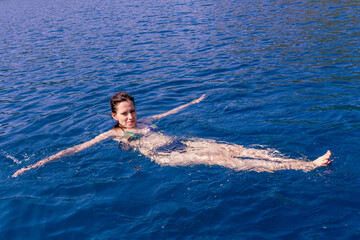 Young woman swimming in deep tranquil turquoise water in open Mediterranean sea