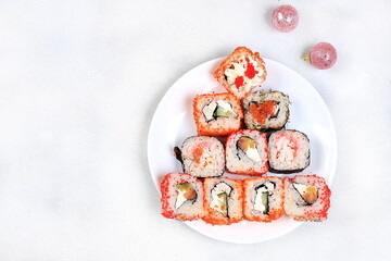 Herringbone made from fresh sushi rolls with sauce on a light, christmas new year food, traditional japanese cuisine, place for text, top view, banner for shop advertisement or invitation
