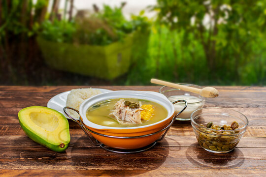 Traditional colombian ajiaco served on orange ceramic dish over rustic wood table