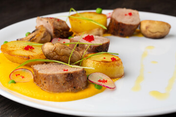 grilled beef steak with potatoes, red caviar and green onions. mustard sauce on a white plate