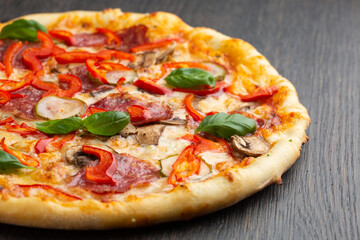 Italian pizza with melted mozzarella cheese, olives and sausage garnished with fresh vegetables and basil leaves