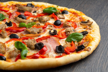 Italian pizza with melted mozzarella cheese, olives and sausage garnished with fresh vegetables and...