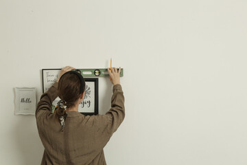 Woman arranging picture frames on wall in new house, diy home improvement concept	