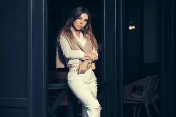 Young fashion woman in white shirt and ripped jeans leaning on railing