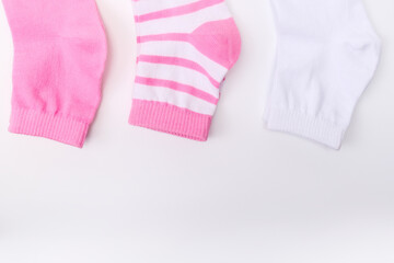 Three socks in pink color gamma, laying from white to pink close up on white background, copy space