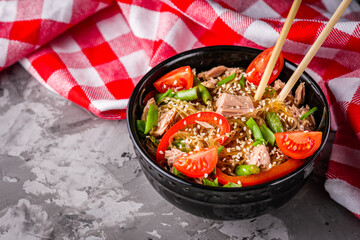 delicious glass noodles with tuna and vegetables on a dark stone background
