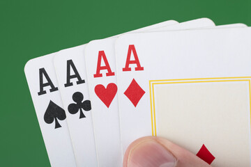 Hand holding 4 aces cards over green background