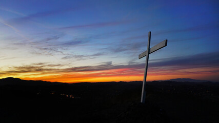 White cross on a hilltop at sunset