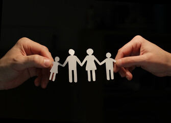 Fototapeta na wymiar A paper family holding hands, forming a chain, with a male and female hand on the sides holding them by the hand, with the sign of union.