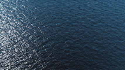 Calm waves in the sea aerial view with sun reflection