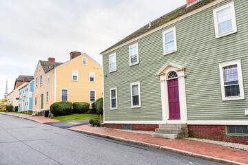 Traditional pastel coloured American wooden houses along a brick sidewalk on a cloudy autumn day. Portsmouth, NH, USA.