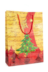 Yellow and red Christmas shopping bag made of paper decorated with a green tree on a white background. New year and gifts concept.