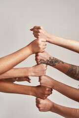 Close up of hands of diverse women putting their fists on top of each other like a team isolated...