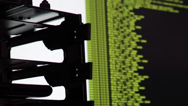 Yellow computer software code moving on a black monitor reflect on glass. Abstract computer hacking in process with rack server base, dynamic text running and flowing on pc screen