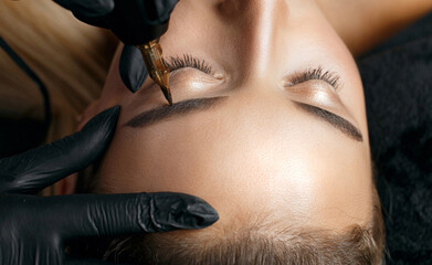 Closeup shot of a woman applying eyebrow permanent makeup