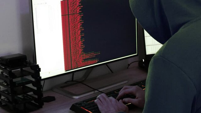 A hacker man writes the red code for an attack. Program a virus with your computer