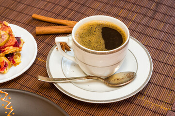 Still life - a hot cup of black coffee, homemade cookies with fruit on a bamboo mat