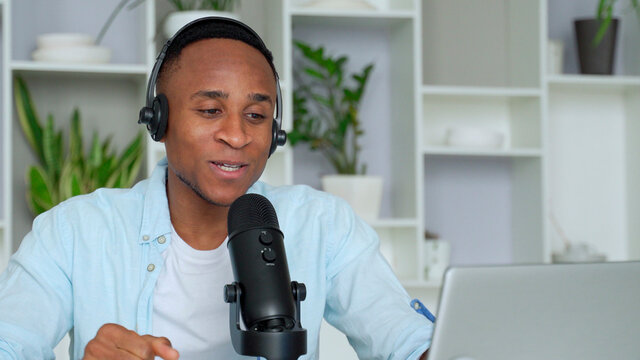 Podcast Concept - Happy Young Black Man Audio Blogger In Headphones With Laptop Computer And Microphone Broadcasting At Home Office