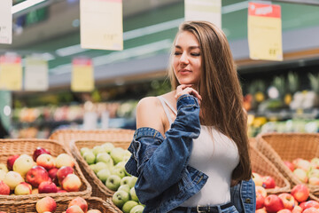 A girl in a supermarket buys apples