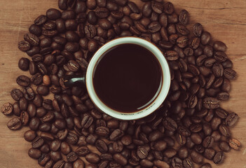 Overhead shot of a black espresso cup with drink on a group of coffee beans