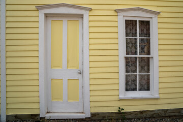 Exterior of a yellow painted home, door and window with white trim. Taken in South Park Colorado, a ghost town