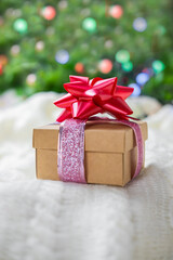 
beautiful festive surprise gift box with a red bow on a bokeh background and near the Christmas tree for new year and valentine's day