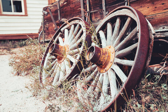 Rusty wagon wheels against a wooden cart, with grass. Useful for rustic backgrounds