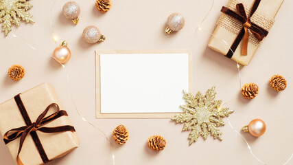 Obraz na płótnie Canvas Christmas card mockup on pastel beige background with gift boxes, golden balls and xmas decorations. Flat lay, top view. Minimal style.