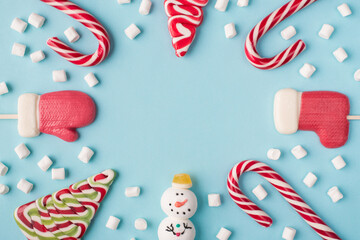 Close up overhead layout photo of funny traditional christmas candies and white marshmallow isolated pastel color background with blank space in center