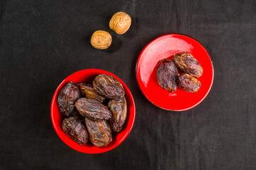 Big luxury dried date fruit in bowls on the dark surface, kurma ramadan kareem concept, close up.