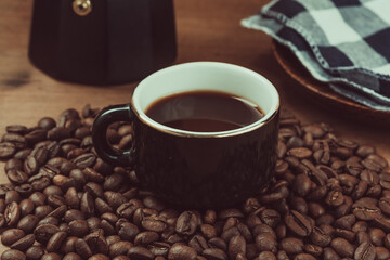 Vintage photograph of black espresso cup, Italian coffee pot and coffee beans on blue with white checkered tablecloth