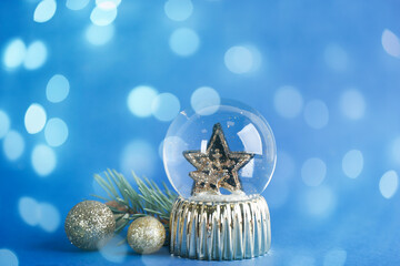 Beautiful Christmas snow globe and decor on blue background, bokeh effect