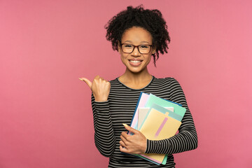 Afro-American tutor or teacher woman isolated on pink studio wall. Student girl wear glasses...