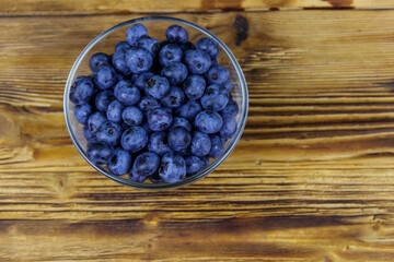 Fresh blueberry in glass bowl on a wooden table. Top view