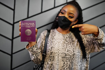 African woman wearing black face mask show Ethiopia passport in hand. Coronavirus in Africa...