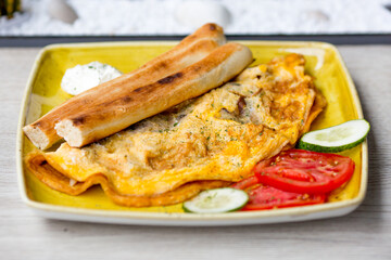 Omelette with tomatoes and cucumber, on yellow plate.