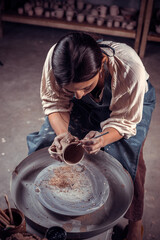 Stylish pottery girl making ceramic pot on the pottery wheel . Handcraft.