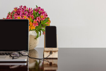 Laptop and smart phone over desktop with flowers