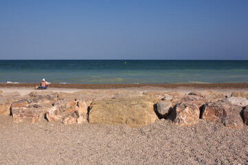 Someone sunbathes on a rocky beach facing the sea