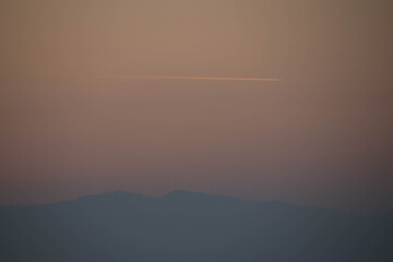 Evening photo on a hill and trace of airplane.