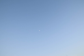 Blue light sky and the half moon.
