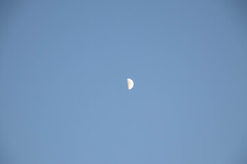 Half moon on a blue sky. Copy space.